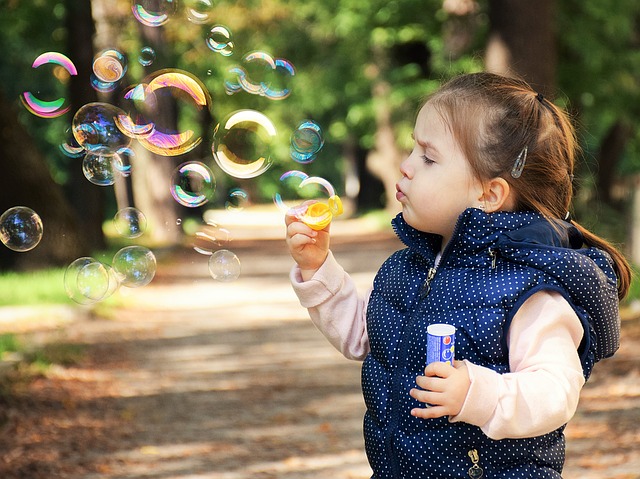 Young girl blowing bubbles outside.